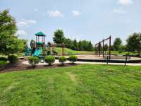 Lots of green space and a playground with seating along the perimeter.