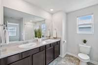 Full primary bath with double vanities, walk-in shower with seating, and large walk-in closet.