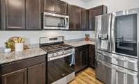 Five gas burners on the stove. The refrigerator is over-the-top with French doors, a double door to the left for frequently used items, water and ice dispenser, a refrigerator drawer, and a large freezer drawer.