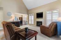 Spacious and inviting den with soaring ceilings, a cozy gas fireplace, and large windows overlooking the private backyard.