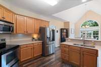 Kitchen features stainless steel appliances, a bar-height counter perfect for stools, and a sunny breakfast room with vaulted ceilings.