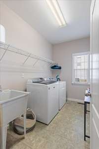 Oversized laundry room with built-in shelving, a deep utility sink, and plenty of space for folding, sorting, or storage.