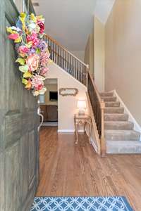 Step inside to a bright, welcoming foyer with high ceilings, warm hardwood floors, and a peek into the dining room on the left