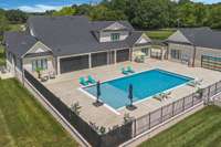 Resort style saltwater pool with sun shelf and fencing around perimeter