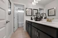 Full guest bathroom upstairs features double vanities, tile flooring, and cultured marble countertops.