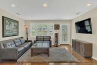 View of the living room from the kitchen. Beautiful picture window and full light privacy glass/   faux leaded glass front door.