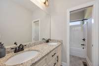 Downstairs, full guest bathroom. There is a double vanity and a sliding door between the vanities and bathroom fixtures for increased functionality.