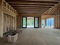 Great room with wood-burning fireplace opening up to outdoor living space. * this home is under construction. Photo taken 6/17/25