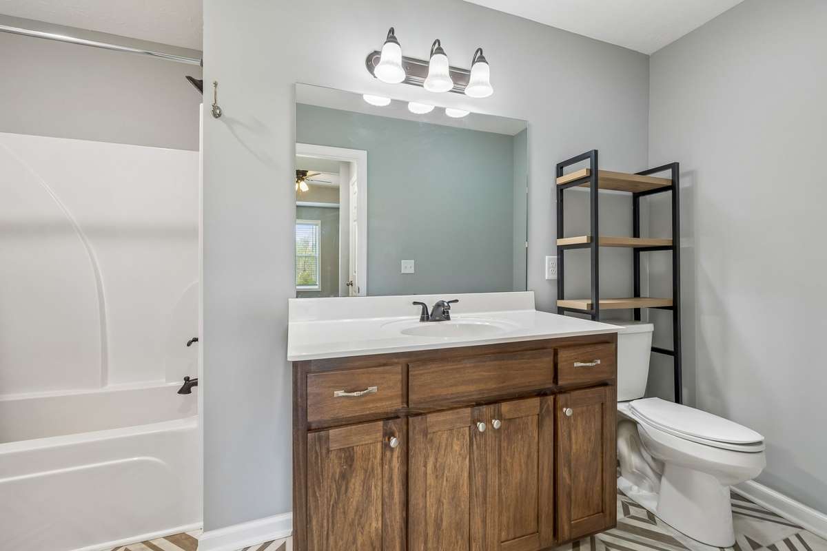 Primary bathroom with functional layout and ample storage. Primary suite offers generous space and access to dual walk-in closets.