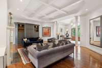 The inviting living room boasts a gracious fireplace flanked by built in bookshelves and a striking coffered ceiling