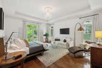 The primary bedroom is a lovely retreat with its trey ceiling, expansive windows and gleaming hardwood floors.