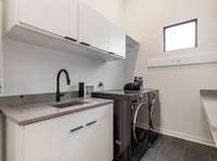 Fully equipped laundry room with utility sink, lots of cabinets, folding counter and front-loading washer & dryer