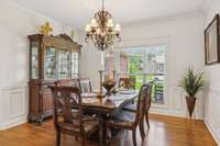 Formal dining room with wainscoting, crown molding, and a large picture window—perfect for holidays or everyday meals.
