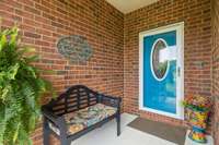 Cheerful blue front door and seating area create a warm, inviting entry that sets the tone for the rest of the home.