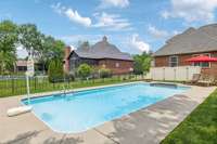 Spacious fenced backyard featuring an in-ground pool and lounging area—perfect for summer entertaining and relaxation.