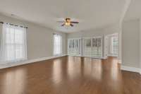Living features a ceiling fan, hardwood floors and access to the screened patio-drapes remain.