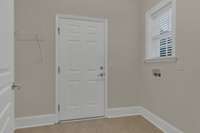 Large laundry area and mudroom with electric washer/dryer hookups, built-in shelving, and direct access to the garage.