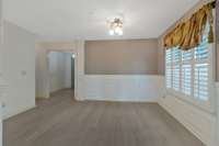 Open concept living room and dining featuring neutral colors with beautiful details like plantation shutters and wainscoting!