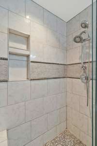 Gorgeous tile work in this custom ensuite shower makes it easy to pamper yourself before relaxing in your primary bedroom!