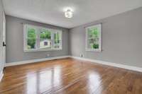 Sun-soaked living room with true hardwood floors and oversized windows that fill the space with natural light.