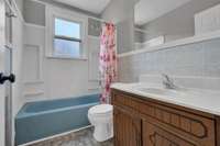 Charming full bathroom with vintage details, a large vanity, and a pop of character from the retro blue tub.