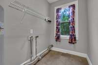 Dedicated laundry space with a window for natural light, tile floors, and built-in shelving for convenience.