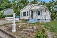 Charming cottage-style home with fresh paint, a welcoming front porch, and classic curb appeal on a quiet street.