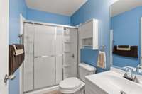 The perfect blend of style and function is a fresh and clean second full bath with a low-entry walk-in shower, bright blue walls, built-in shelving, and updated fixtures!