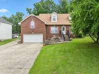 Inviting property featuring full-growth trees in both the front and back yards. Plenty of grass surrounds the home, creating a welcoming outdoor setting. The spacious driveway provides ample parking for multiple vehicles.