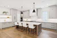 Gorgeous kitchen with oversized island, tons of counter space, designer lighting and counters, custom cabinetry and built-in appliances