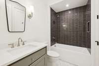 En-suite bathroom with custom cabinetry and designer tile and lighting selections