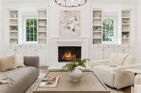Gorgeous open living space with designer lighting, built-in shelving and cabinetry, stucco fire place and ceiling to floor four-panel sliding glass door