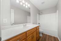 The main hall bath is well appointed with vinyl hardwood floors, oak vanity, neutral paint and a tub/shower combo.