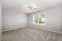 The primary bedroom with new carpet, ceiling fan, neutral paint and double window overlooking the backyard.