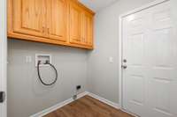 The utility room off the kitchen leads into the garage. It features oak cabinets for storage as well as a double door pantry closet.