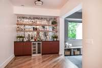 The wet bar has a wine fridge, mirrored tile backsplash, and soapstone counter.