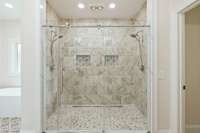 Huge walk in shower with linear drain, 2 shower heads and 2 niches.