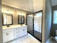 Owner's Bath with Sparkling White Cabinets & Spacious Custom Tile Shower.