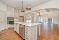 Gorgeous kitchen features quartz counters, large island, stainless appliances, accent arches, custom built soft-close cabinets.
