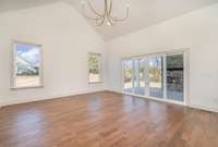 Living room features cathedral ceiling, chandelier, and double sliding glass doors to covered porch.