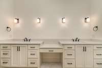 Primary bathroom features large space with double vanities and sconce lighting (mirrors installed upon buyer request.)