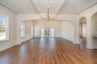 Kitchen opens to dining area with ceiling beam accents, arched doorways, tall ceilings, and lovely chandelier.