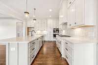 Quartz countertops, under cabinet lighting, gas cooktop with custom range hood, built in oven + microwave combo, tile backsplash, soft close cabinets.... no detail missed in this kitchen!