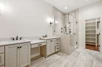 Primary bathroom features quartz counters, vanity seating area, double vanities