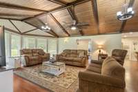 18x27 Living Room with wood plank vaulted ceiling with ample tall grid free energy efficient windows overlooking the covered front porch and front yard with mature trees.