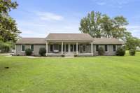 Large covered front porch overlooking the large front yard with mature trees
