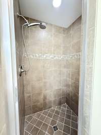 Primary Bath has custom tile shower with clear shower door