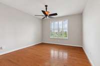 Primary bedroom on the main level with ceiling fan and plantation shutters on the windows