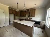 Kitchen with gas range, quartz tops and wood hood