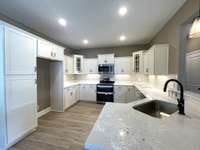 Kitchen with gleaming White Cabinetry highlighted with Corner Glass Doors, Quartz tops & Tile Backsplash !!!!
